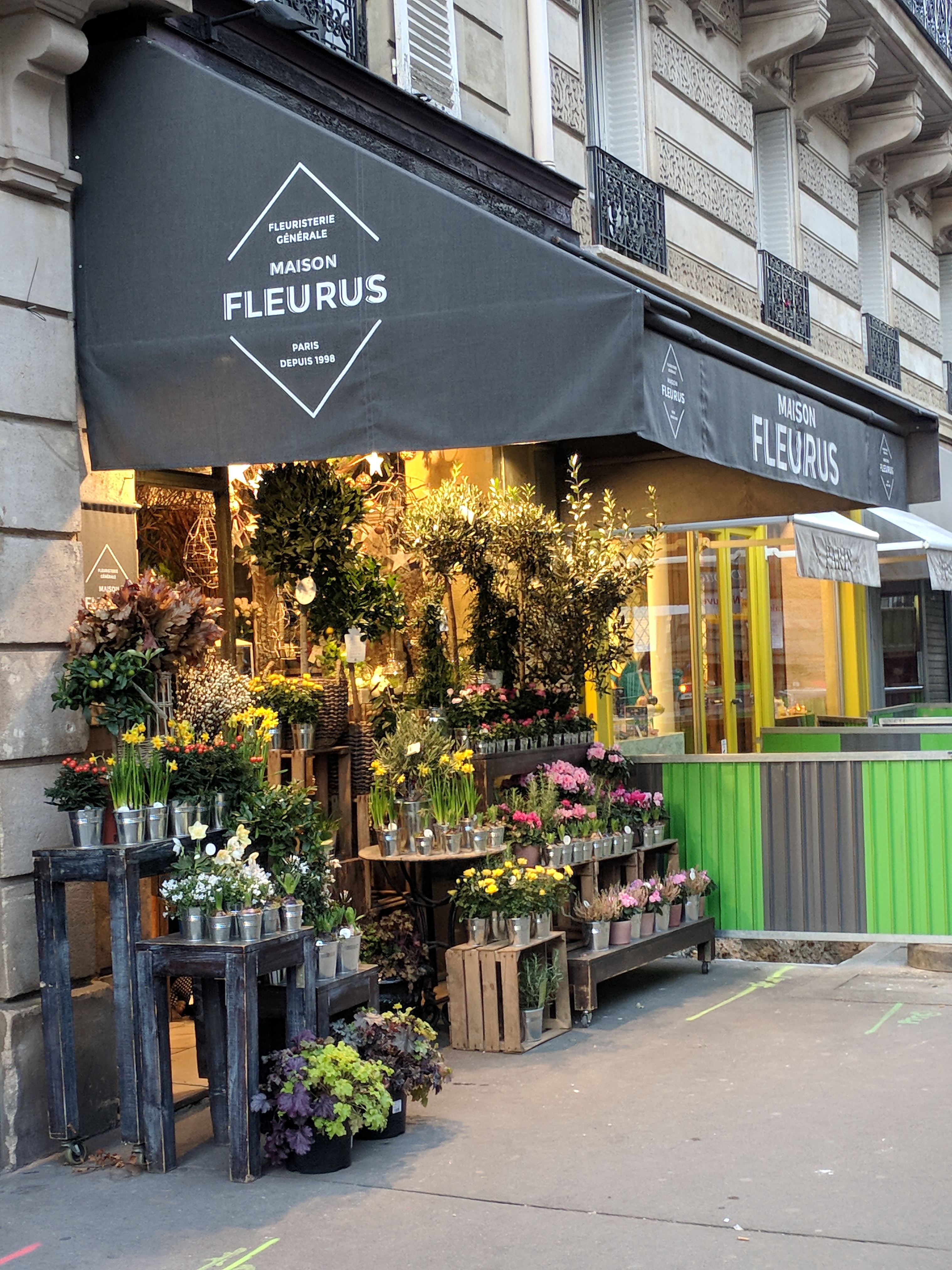 An inviting flowershop store front overflowing with plants.